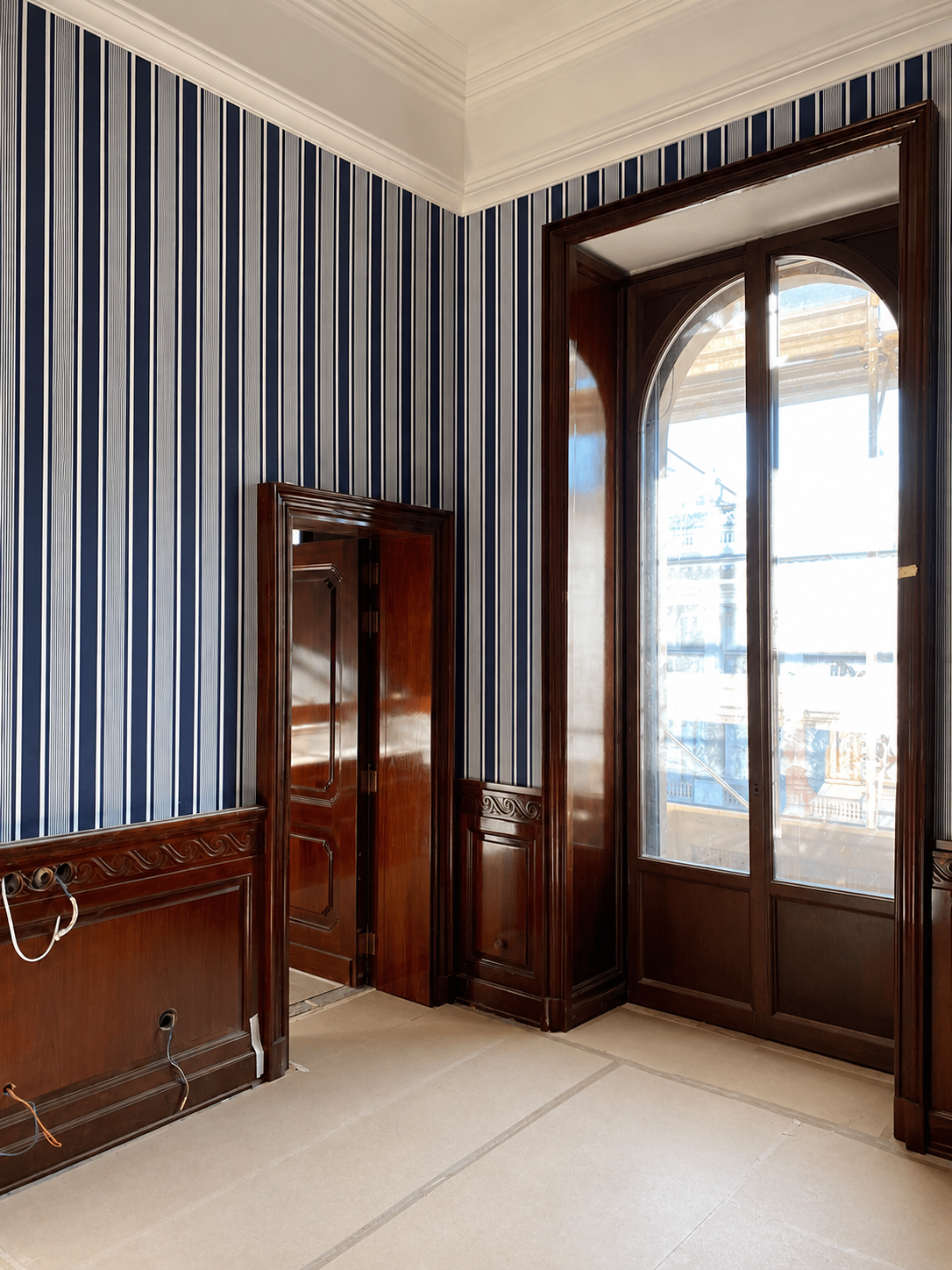Mahogany joinery in position — the palazzo's arched windows and scaffolding visible during active fit-out